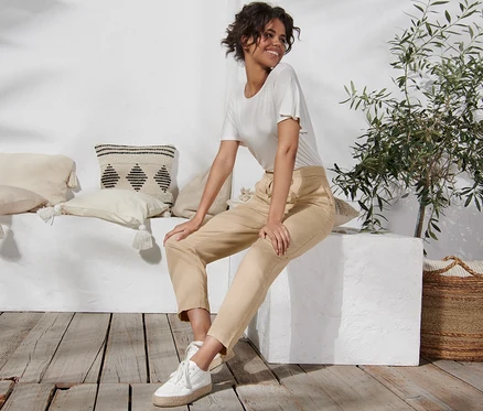 Une femme est assise sur un bloc blanc et porte un pantalon en mélange de lin.
