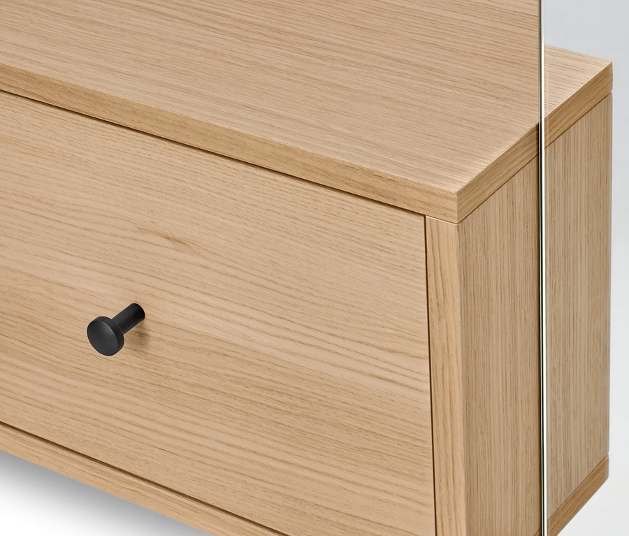 Gros plan d'une commode en bois clair avec tiroir, une poignée ronde noire et un miroir. Garde-robe avec miroir.