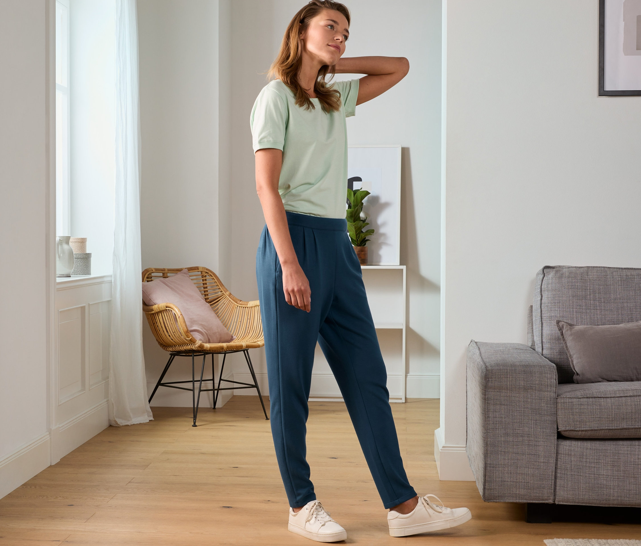 Femme posant en t-shirt vert et pantalon de jogging.