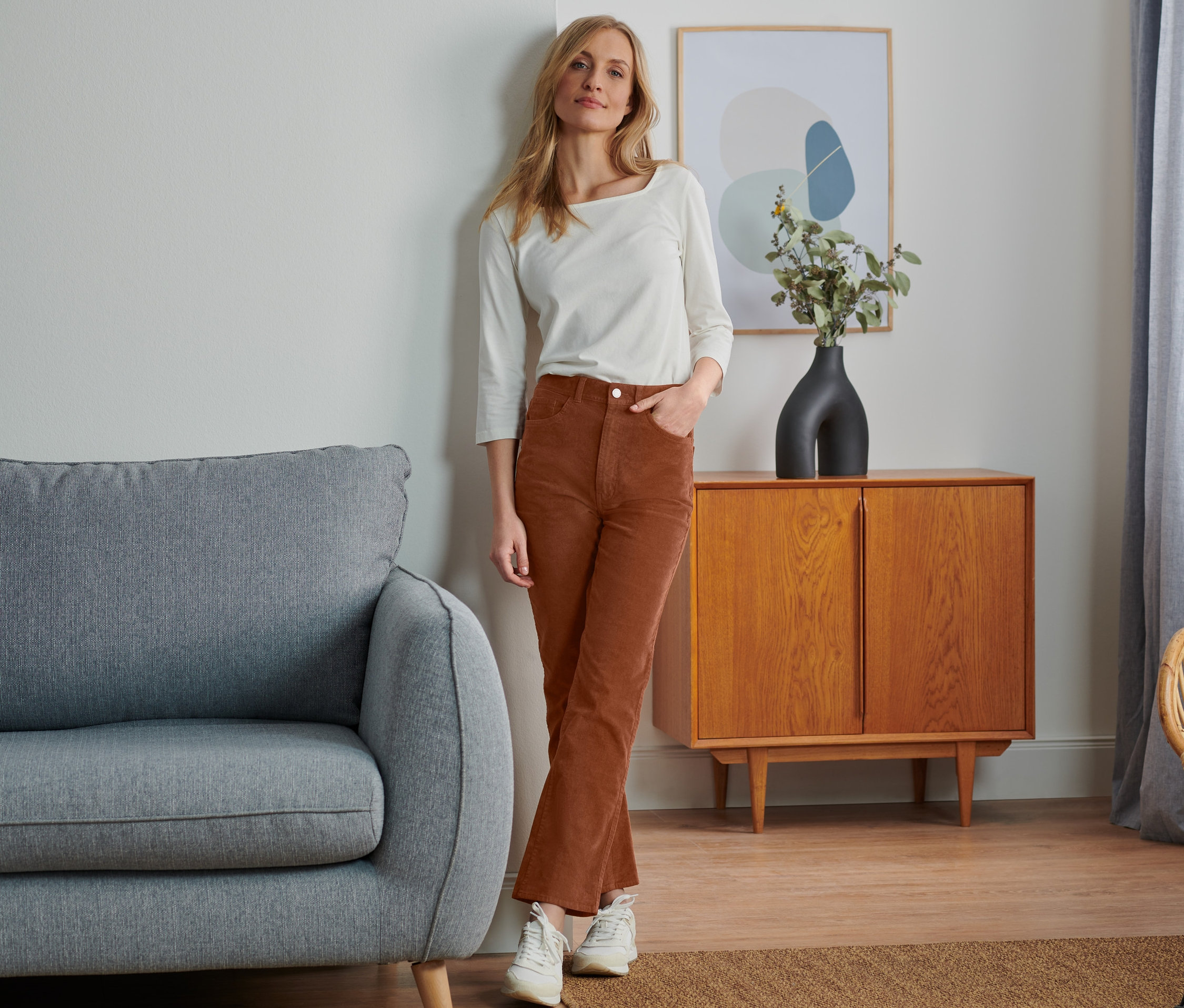 Femme posant en pantalon évasé en velours côtelé et haut blanc.