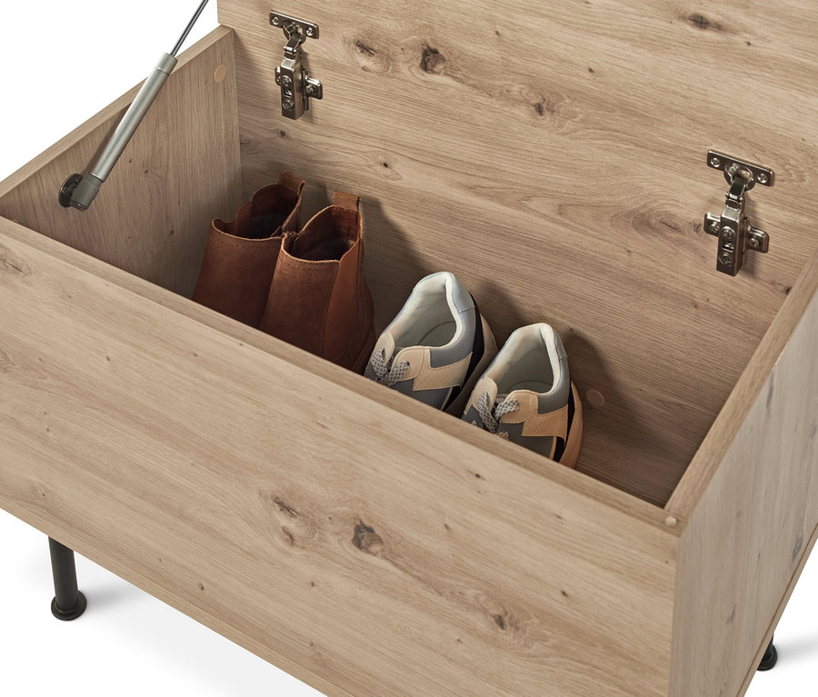 Un banc ouvert avec compartiment de rangement contenant deux bottes marrons et deux paires de baskets.