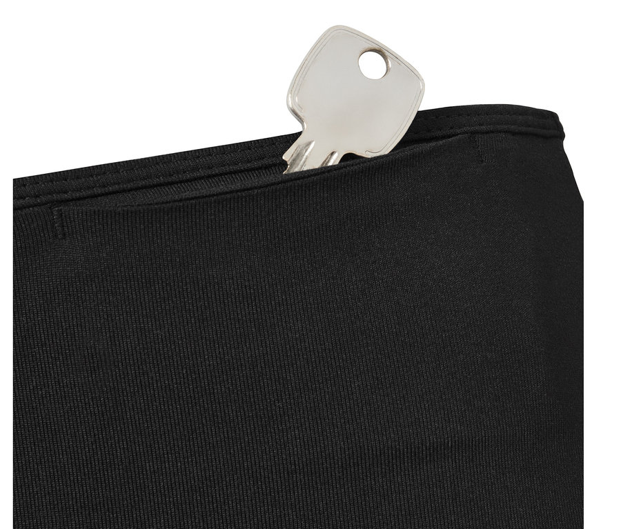 Une clé argentée dans la poche d'un legging de sport noir.