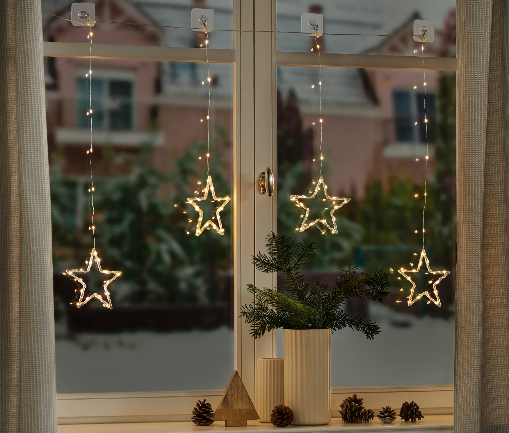 Quatre rideaux lumineux à LED avec des étoiles suspendus à la fenêtre.