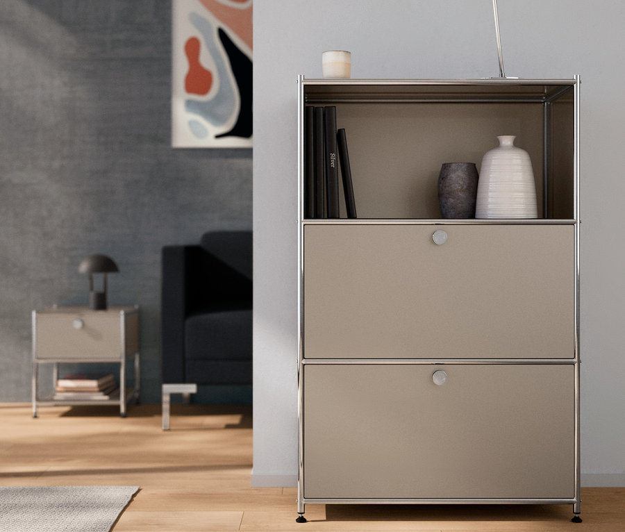 En intérieur, commode en métal « CN3 » à 2 abattants, taupe. Une lampe de table en métal chromée est posée sur le dessus.