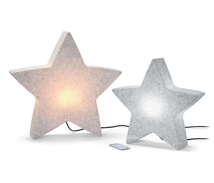 Deux lampes smart d’extérieur « étoile », une de taille L et une de taille S, sont placées côte à côte sur un fond blanc. Un téléphone portable est posé entre les deux.