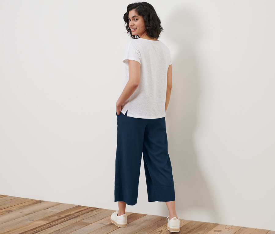 Femme regardant par-dessus son épaule et posant dans un pantalon palazzo en lin mélangé.