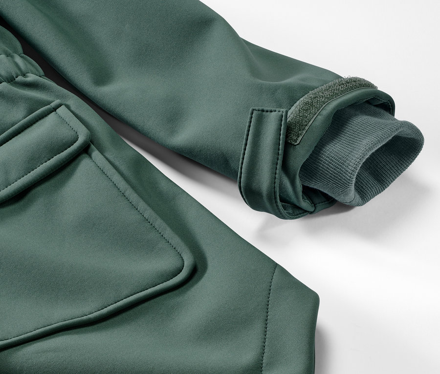 Détail d'un manteau en softshell vert pour enfant avec poche et manchette.