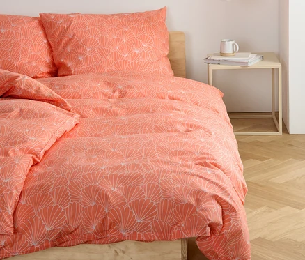 Sur un lit, une parure de lit en renforcé à motifs floraux.