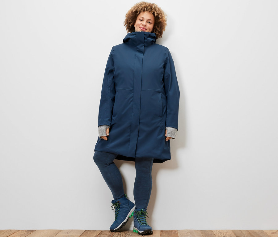 Femme posant en legging de sport et manteau technique 3 en 1 avec gilet sans manches.