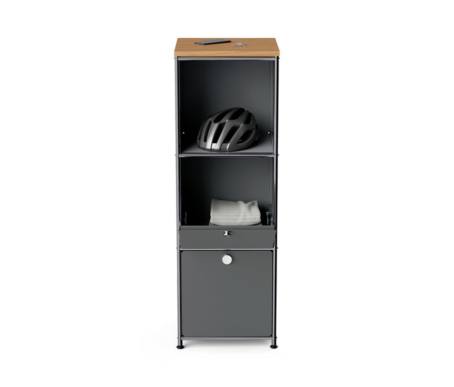 Commode étroite en métal gris « CN3 » avec plateau en bois et 2 abattants. Un casque et une serviette sont posés sur le dessus.