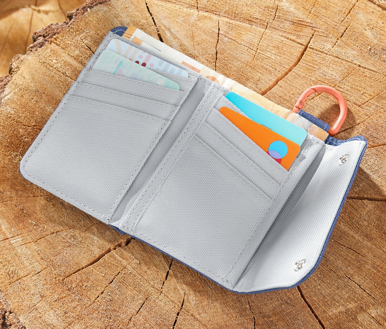 Un portefeuille outdoor ouvert est posé sur une souche d'arbre à côté d'une carte et d'une pomme.