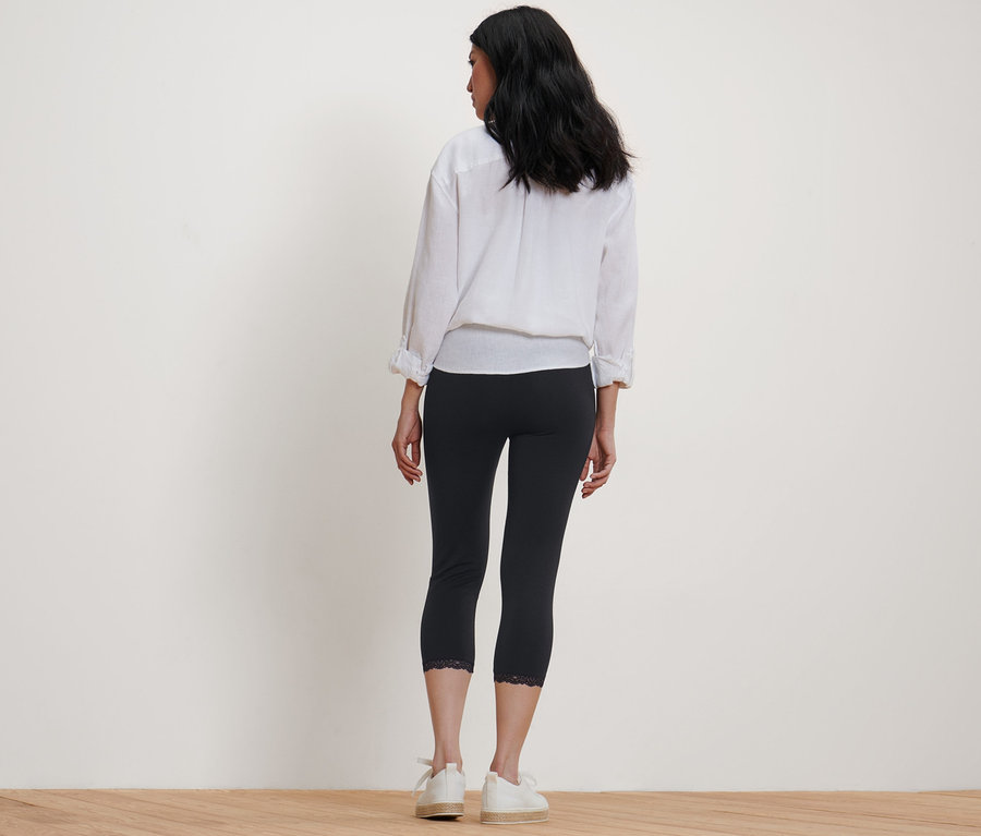 Une femme, vue de dos, porte un legging 3/4 noir avec bordure en dentelle.