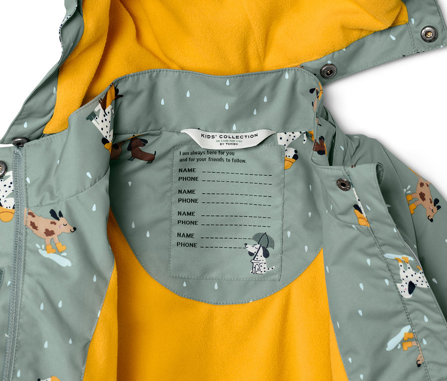 Gros plan sur une veste de pluie thermique pour enfant avec un imprimé de chiens et une doublure jaune.