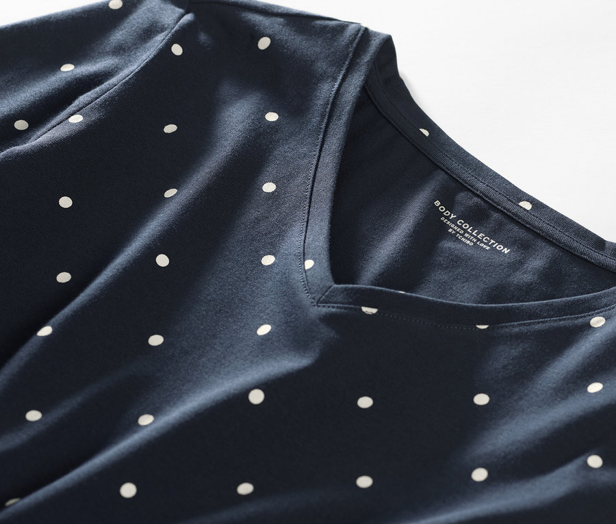 Gros plan d'une chemise de nuit bleu foncé à pois blancs.