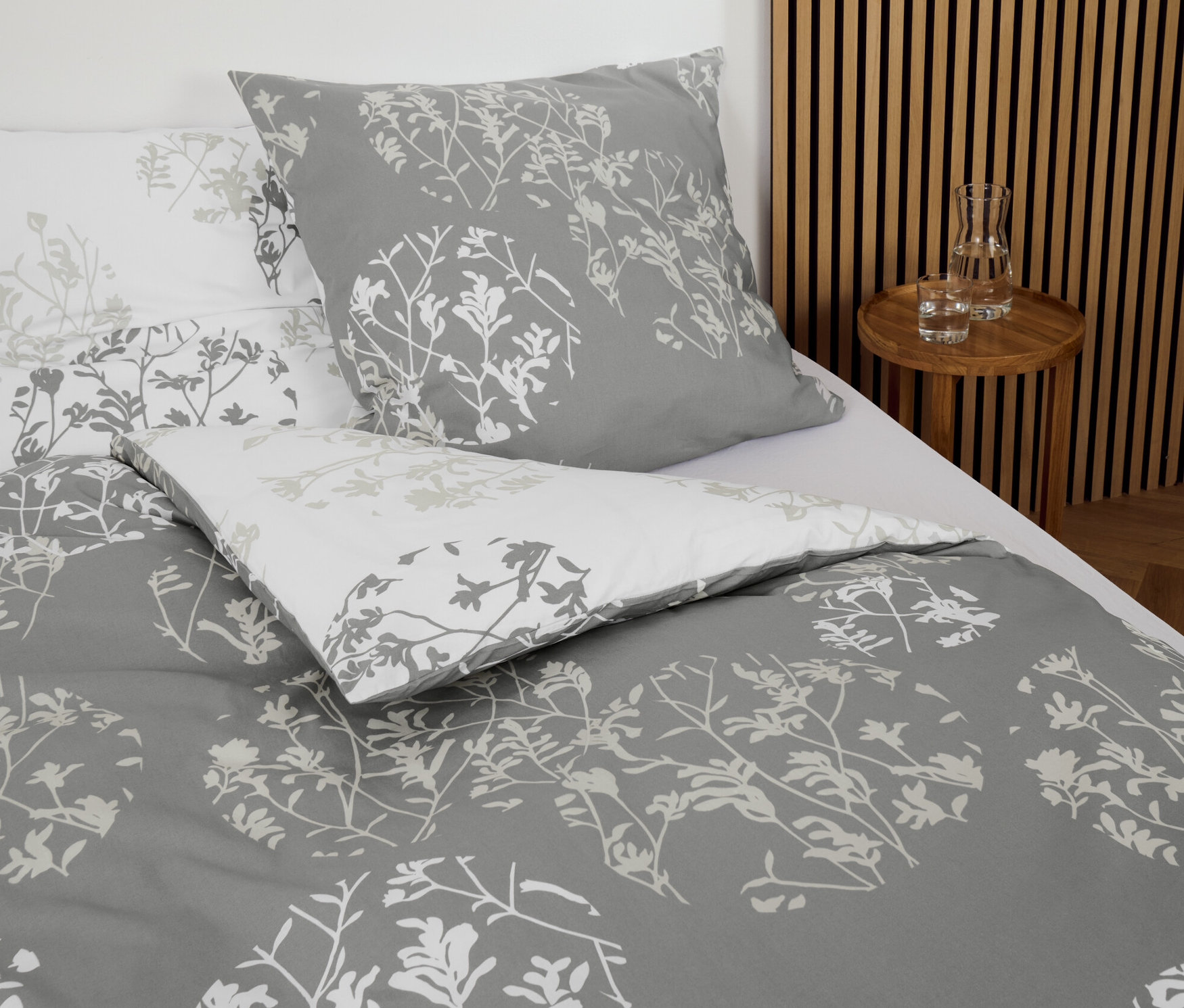 Parure de lit grise en renforcé avec motif floral sur un lit.