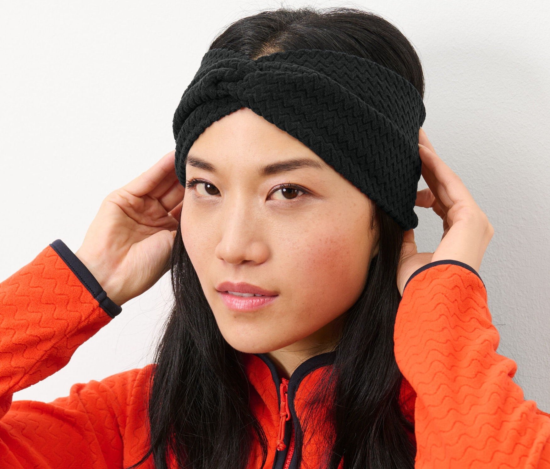 Une femme ajuste son bandeau frontal en polaire noir.