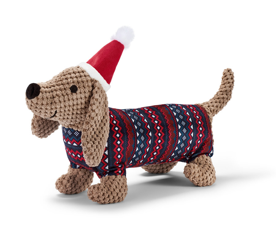 Un jouet en peluche pour chien « teckel » porte un bonnet de Noël et un pull.