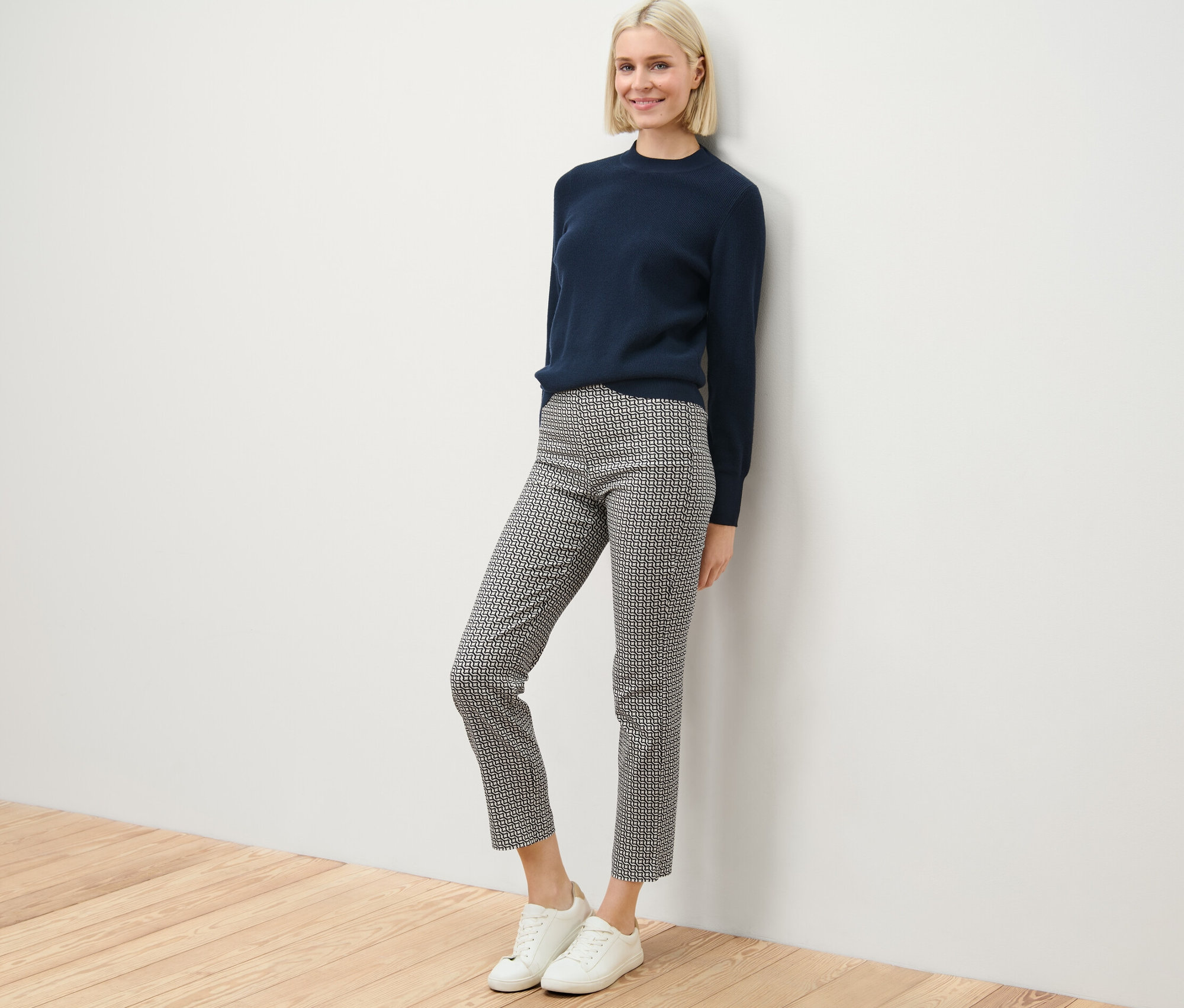 Femme posant en pull bleu marine et pantalon stretch imprimé.