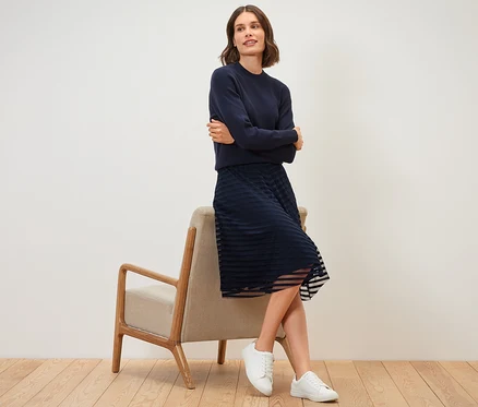 Femme assise sur une chaise portant une jupe en mesh.