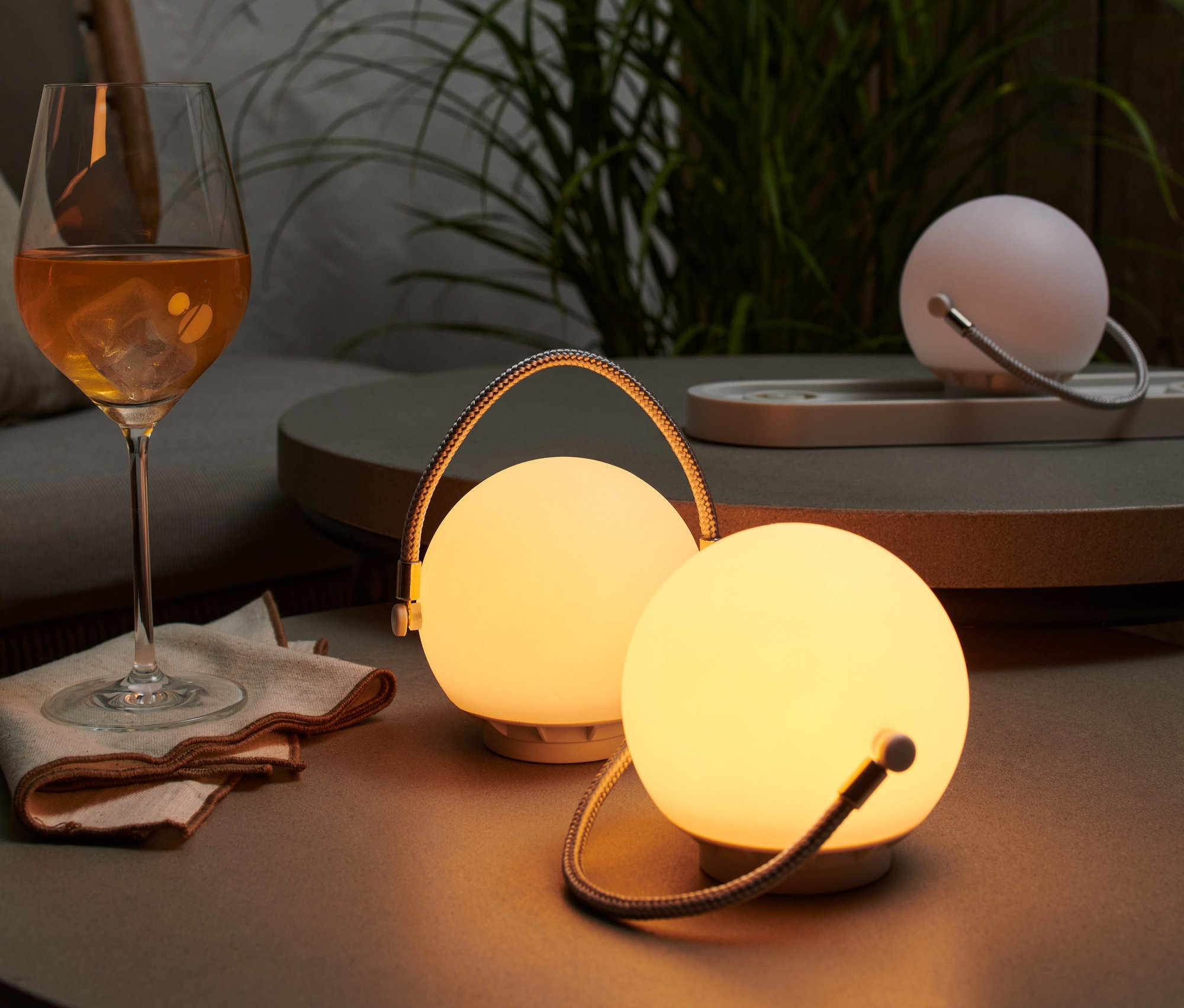 Sur une table, un ensemble de lampes de table à batterie à côté d'un verre de boisson.