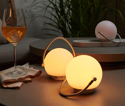 Sur une table, un ensemble de lampes de table à batterie à côté d'un verre de boisson.