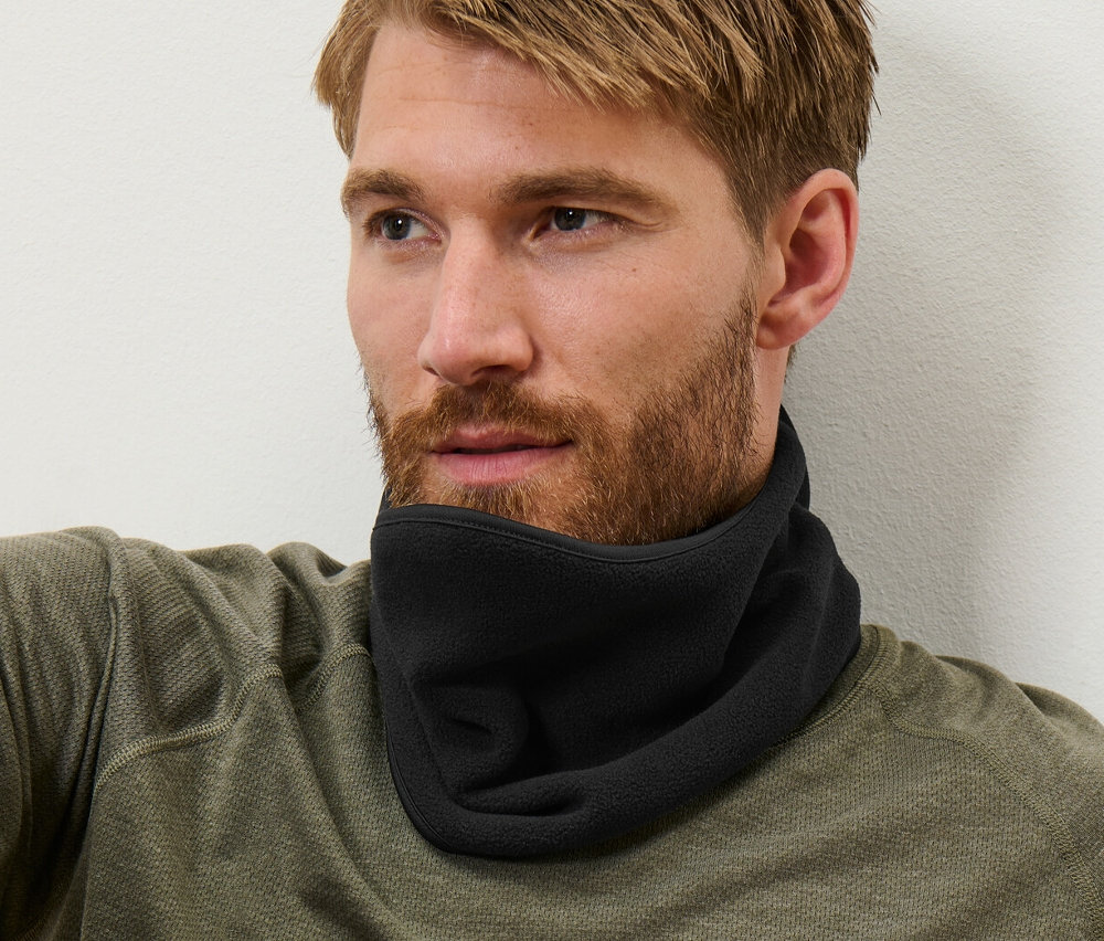 Homme aux cheveux bruns assis portant un col en polaire noir.