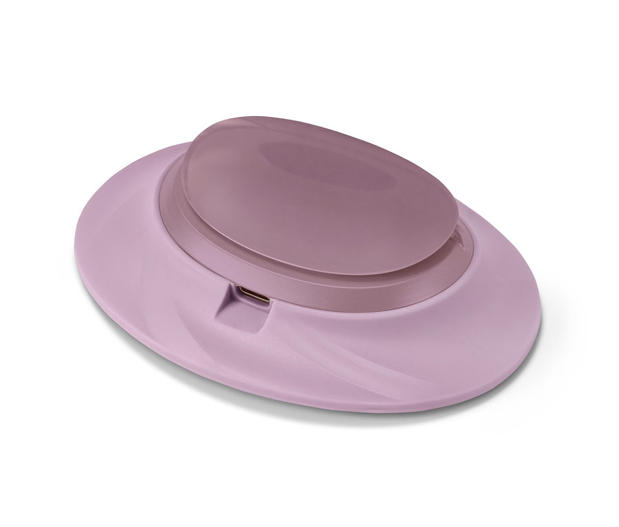 Un chauffe-ventre sans fil rose clair sur fond blanc.