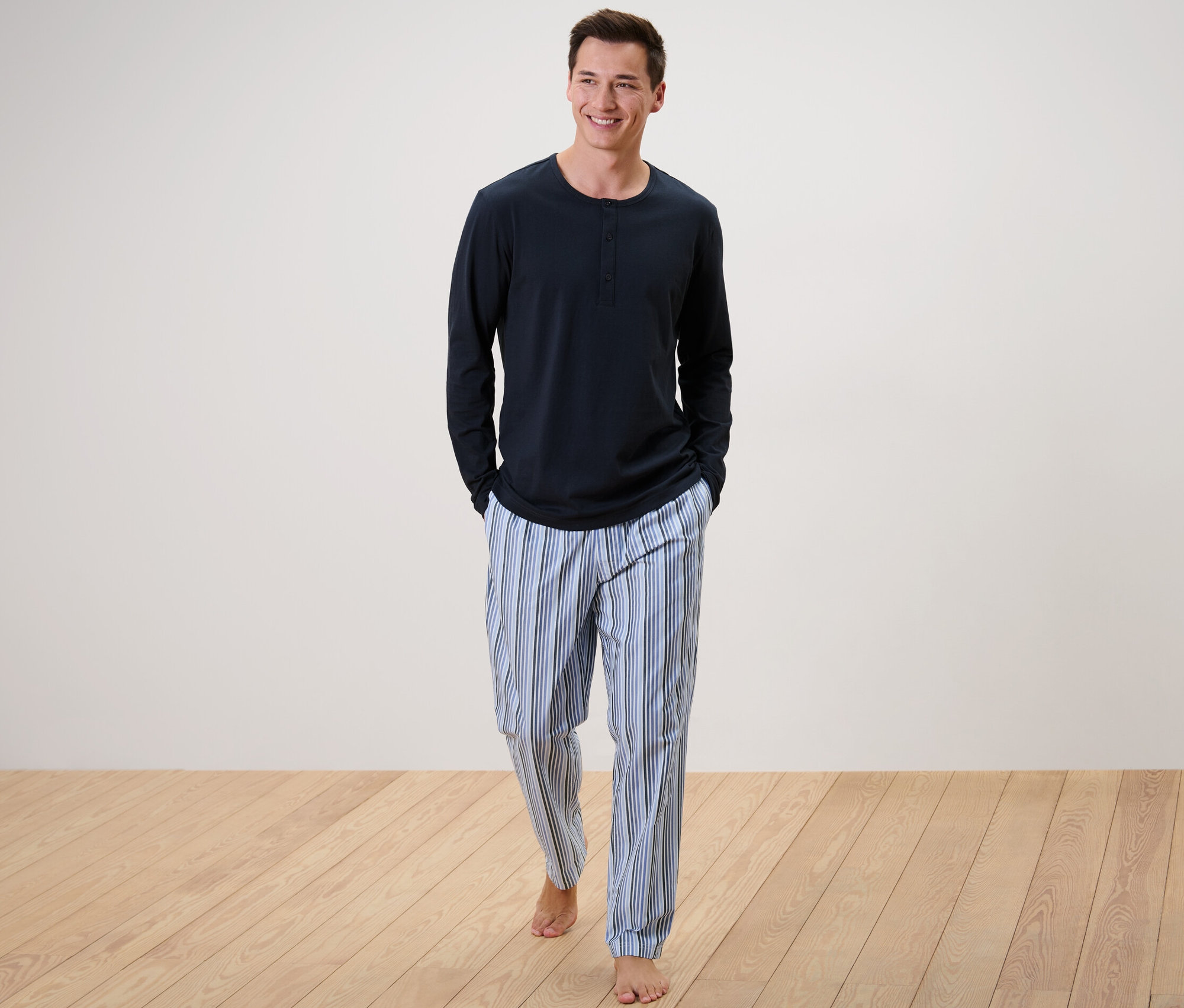 Un homme marche et porte un pyjama avec un pantalon tissé.