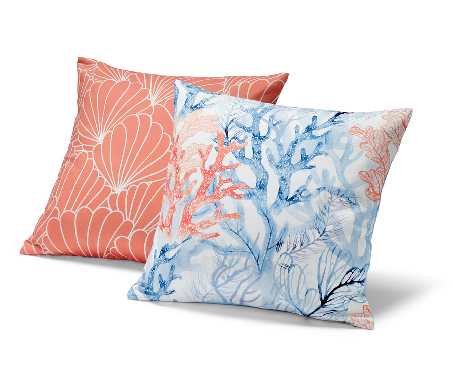 Deux housses de coussin décoratif : une corail avec un motif géométrique blanc, l’autre avec des coraux bleus et corail.