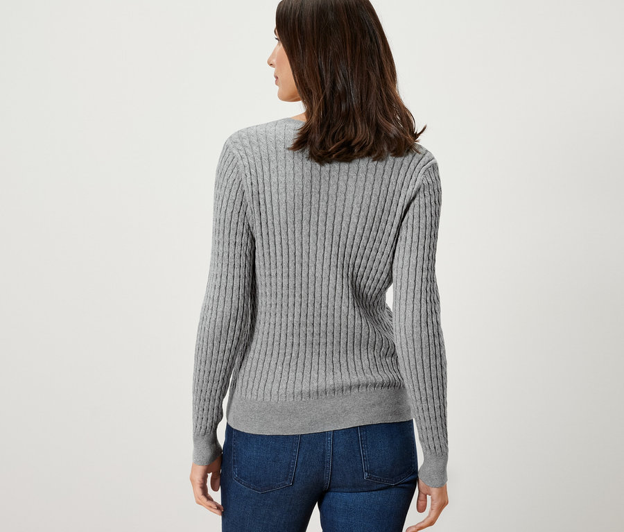 Femme portant un pull en maille torsadée gris.
