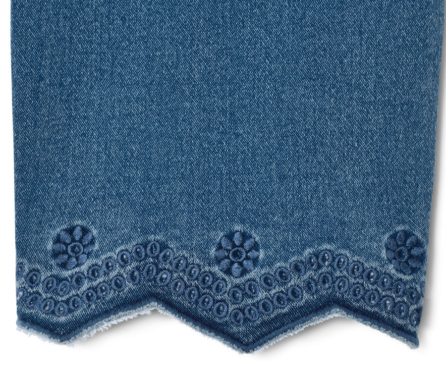 Détail d'un tregging 7/8 bleu avec broderie ajourée à l'ourlet.