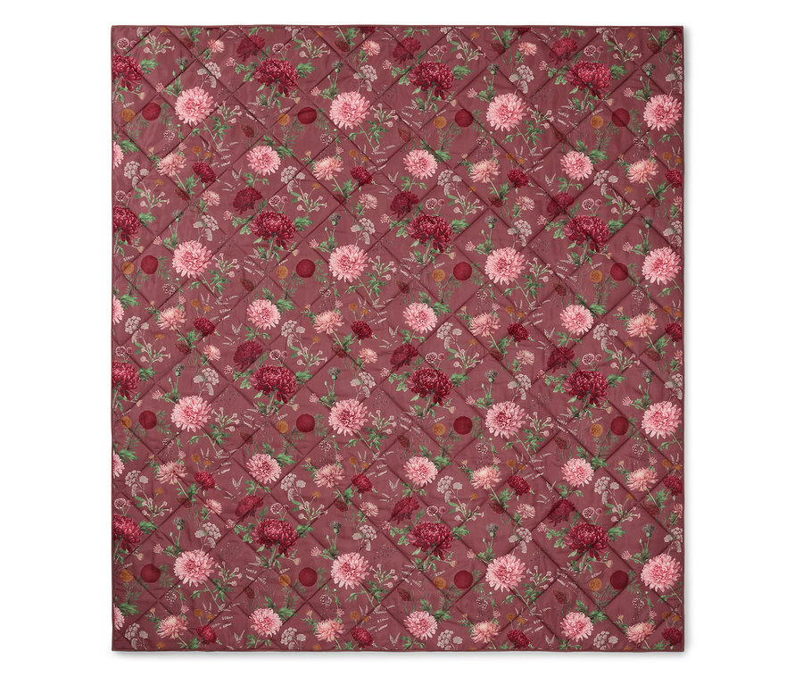 Couverture matelassée avec motif floral dans les tons rose et bordeaux.