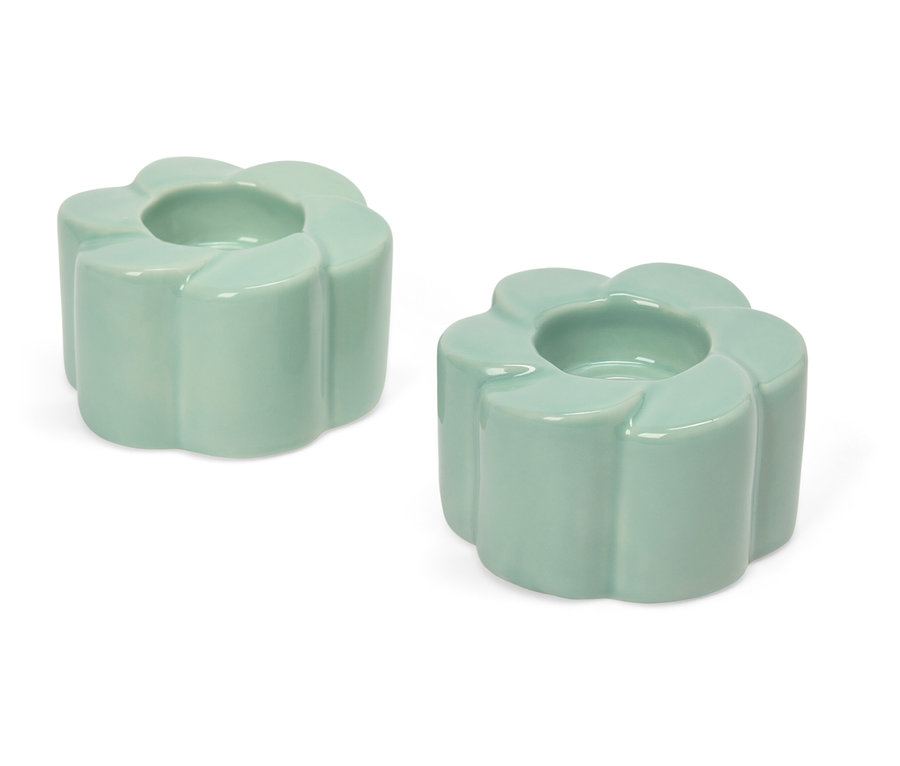 Deux bougeoirs vert clair en forme de fleur sur fond blanc.