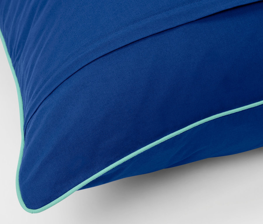 Gros plan d'une parure de lit en renforcé bleu de taille standard avec une bordure turquoise.