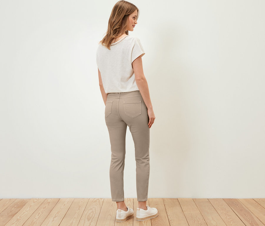 Une femme se tient dos à la caméra et porte un tregging 7/8, un t-shirt et des chaussures.