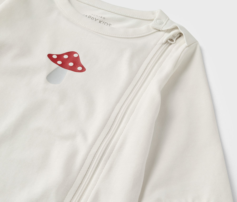 Gros plan sur un pyjama bébé rose et blanc avec une illustration de champignon et une fermeture éclair.
