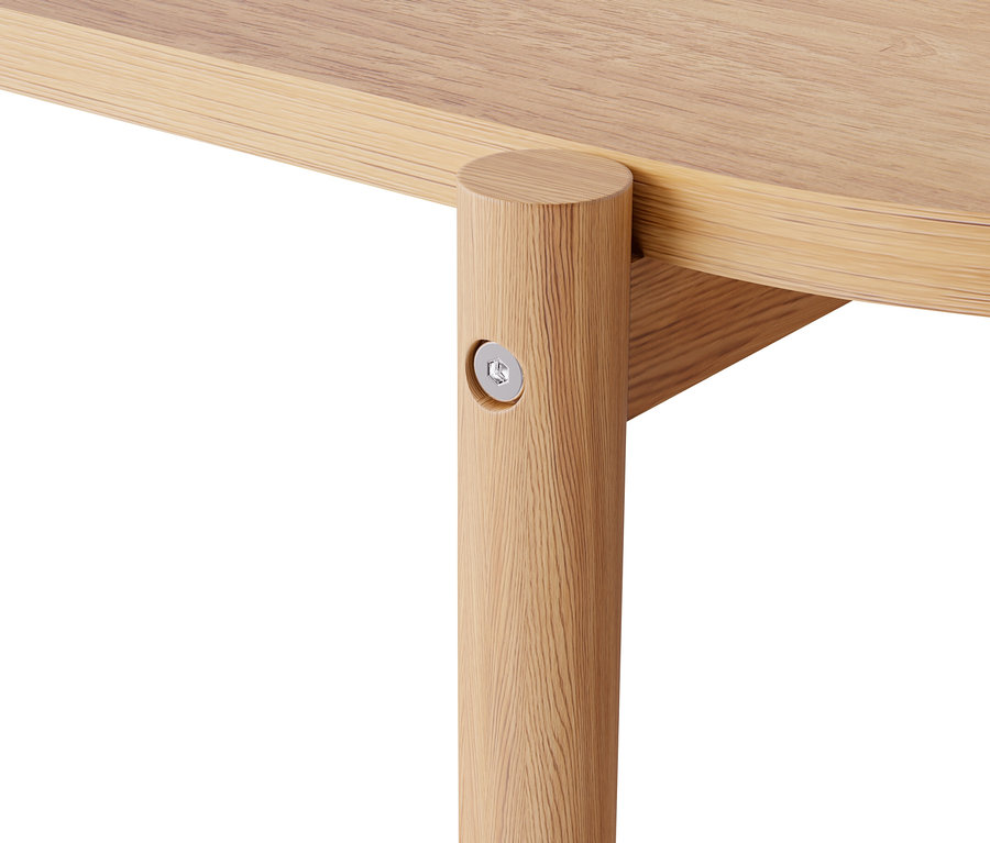 Détail du coin d'une table avec un pied en bois clair verni.
