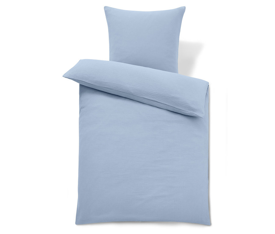 Linge de lit bleu clair avec un oreiller sur le dessus.
