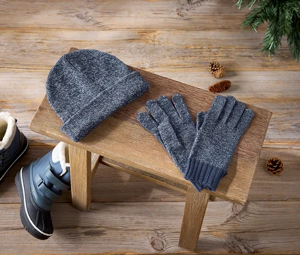 Bonnet bleu, gants et bottes d'hiver sur un tabouret en bois.