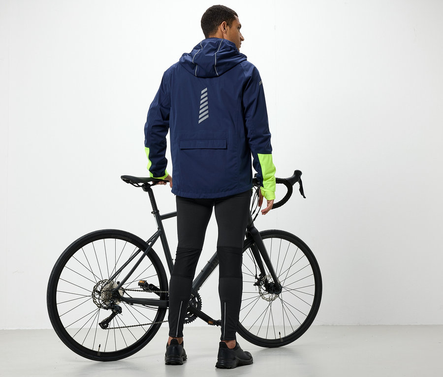 Un homme en veste à capuche se tient à côté d'un vélo.