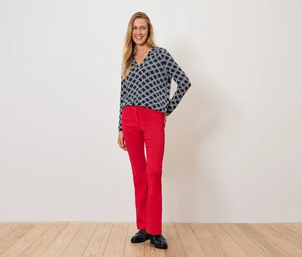 Une femme portant un haut bleu et blanc et un pantalon rouge se tient sur un plancher en bois.