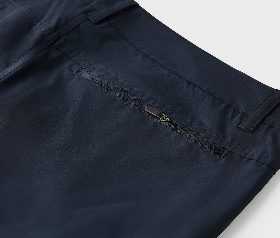 Gros plan d'un pantalon bleu marine avec une poche zippée.