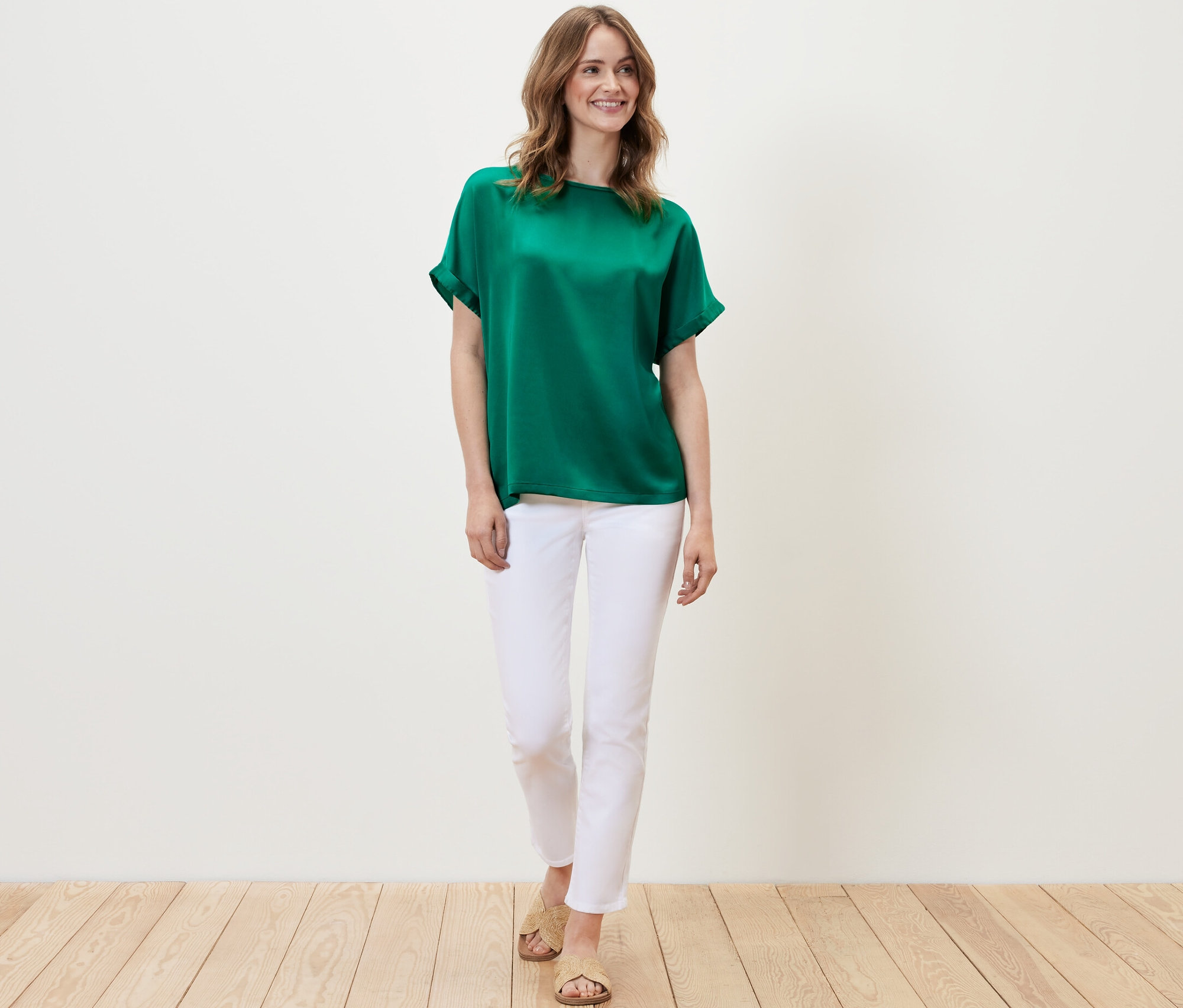 Femme portant une blouse bimatière turquoise et un pantalon blanc.