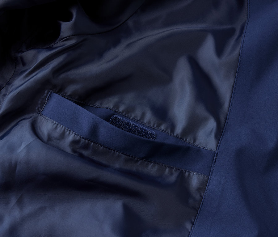 Gros plan sur l'intérieur d'une veste technique outdoor bleue avec poche intérieure.