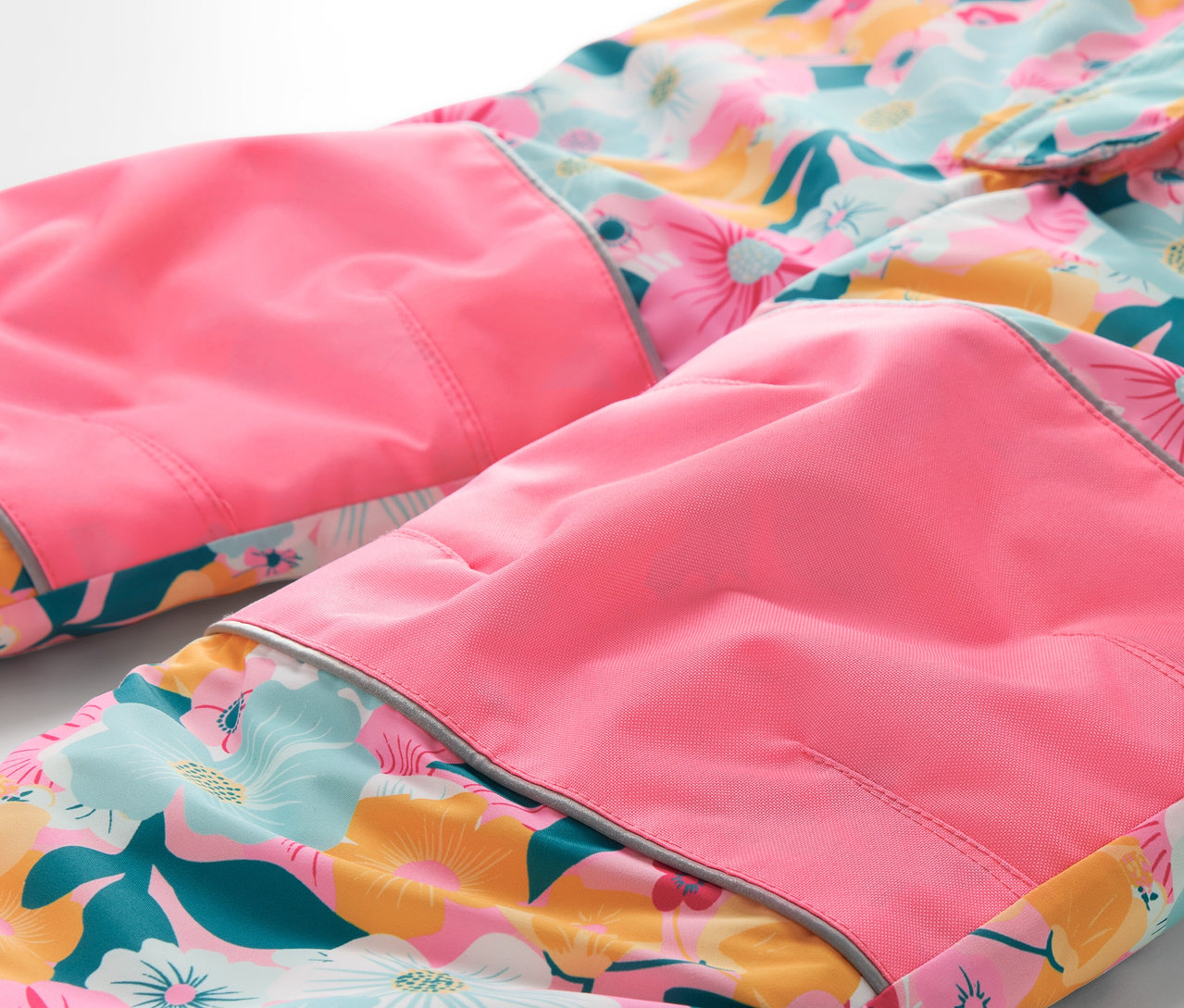 Détail d'un pantalon à fleurs avec des genoux roses.