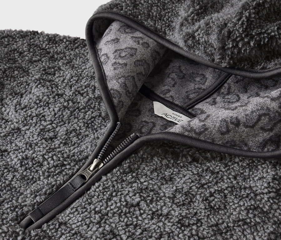 Gros plan sur un sweat à capuche gris en fausse fourrure avec fermeture éclair et motif animalier gris à l'intérieur de la capuche.