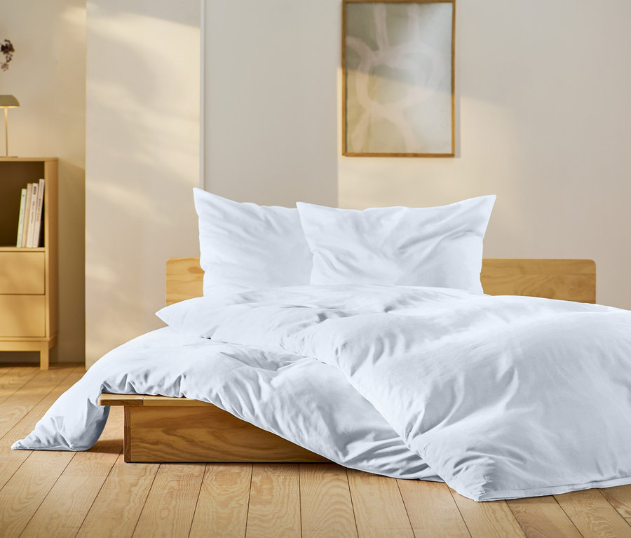 Chambre avec lit en bois avec des draps blancs, une table de chevet en bois et des décorations.