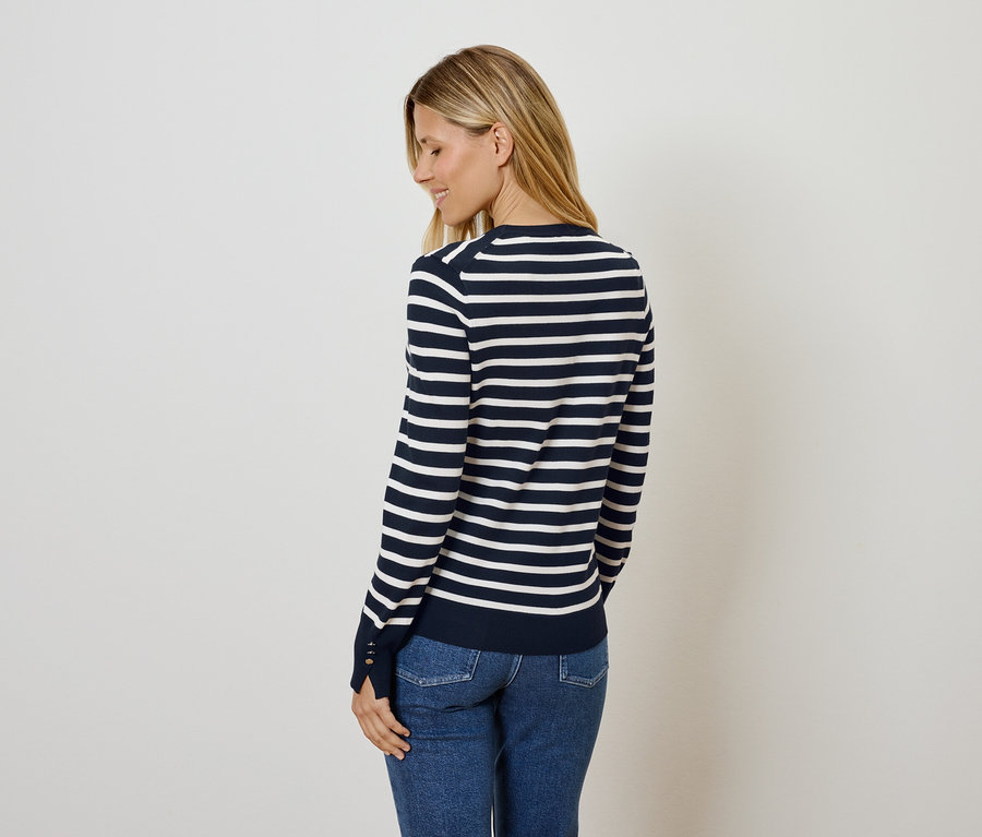 Femme posant en pull rayé bleu et blanc et jean.
