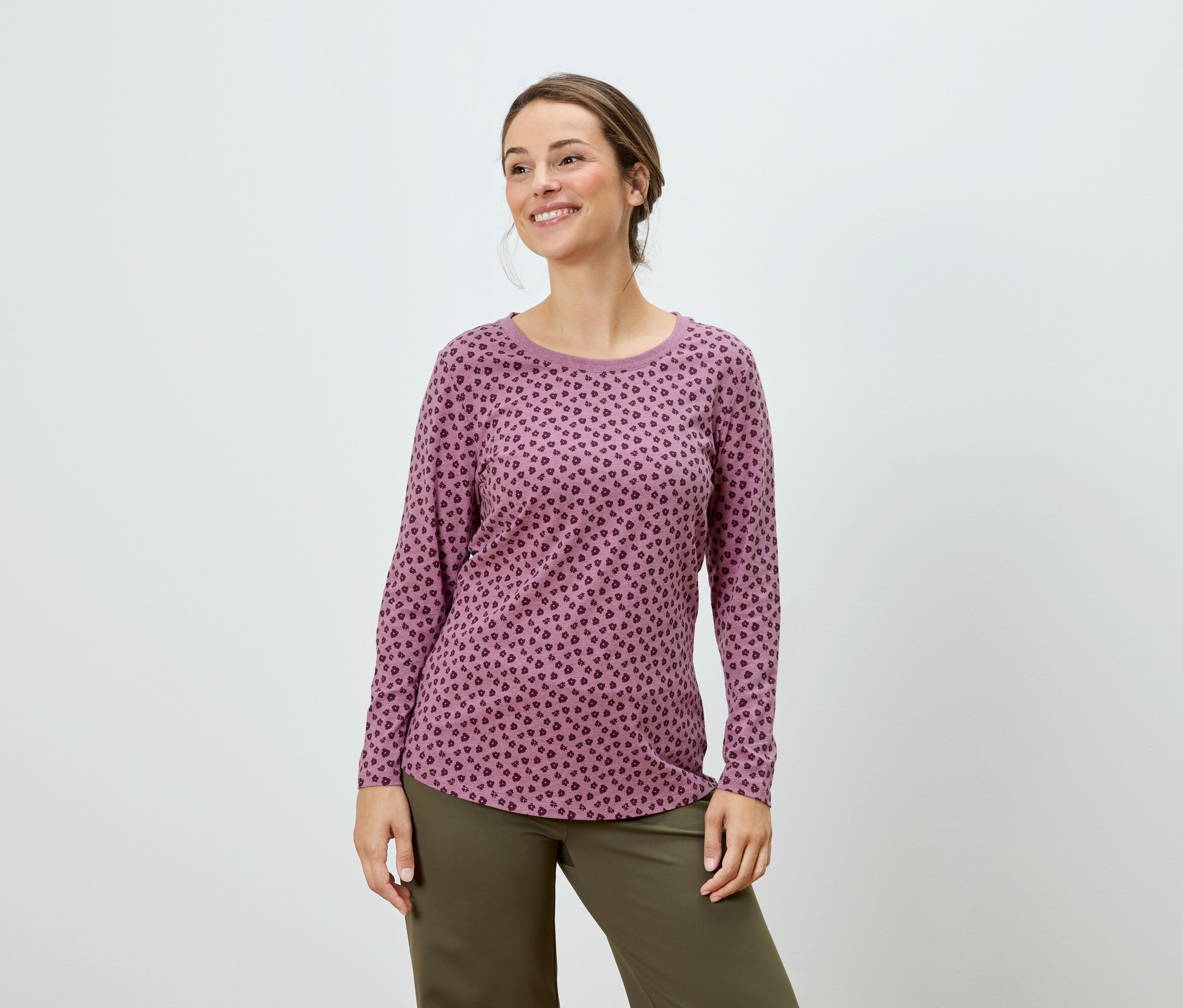 Femme posant dans un haut à manches longues rose à pois et un pantalon vert.