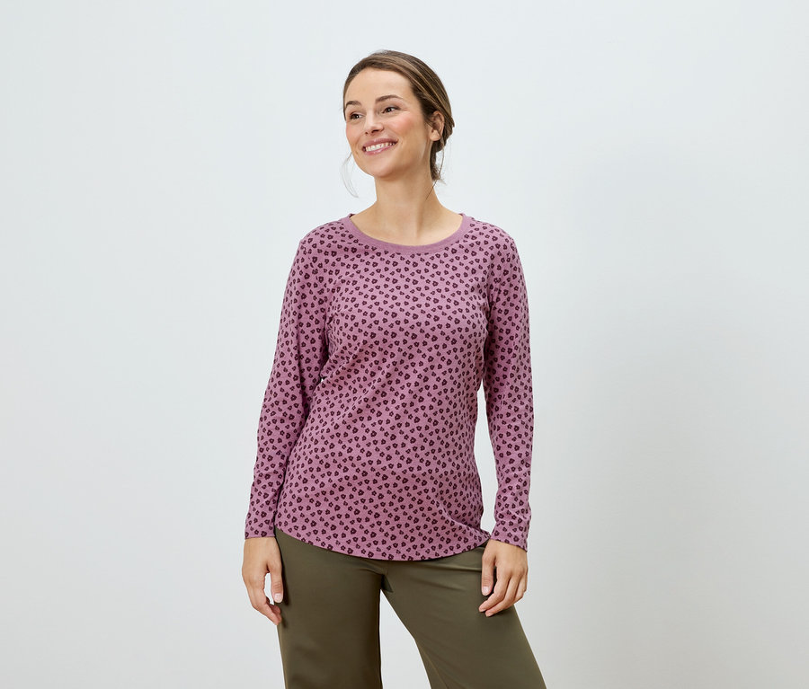 Femme posant dans un haut à manches longues rose à pois et un pantalon vert.